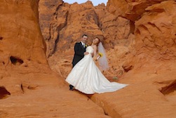 Photo of a Valley of Fire wedding with the groom and bride posing at the entrance of a red sandstone canyon.